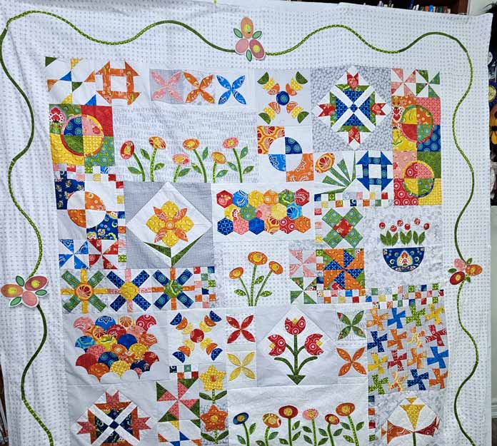 A colorful quilt with a white border and a gree motif
