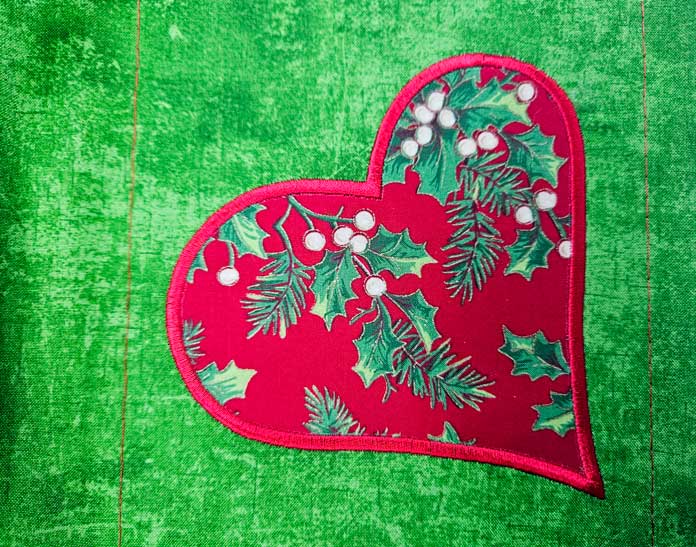 A red heart on green fabric; HeatnBond FeatherLite, applique, machine embroidery, fabric projects