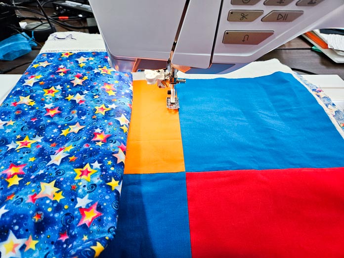 A bright-colored quilt under the presser foot of a sewing machine