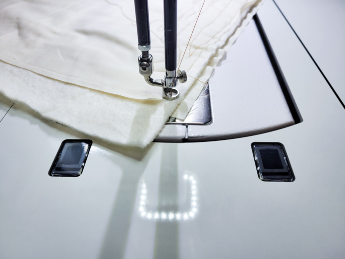 A reflection of the front LED lights on the sewing machine on the white sewing table; Husqvarna Viking PLATINUM™ Q160