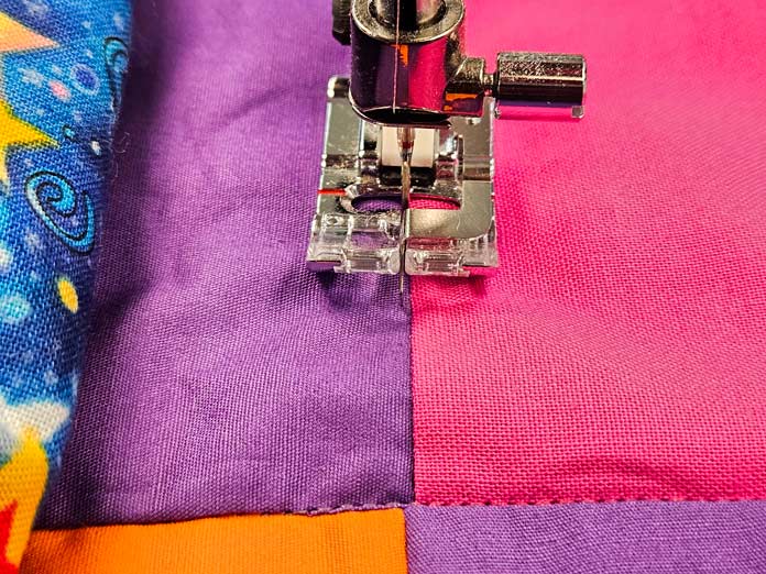 A bright-colored quilt under the presser foot of a sewing machine; Husqvarna VIKING DESIGNER EPIC 3