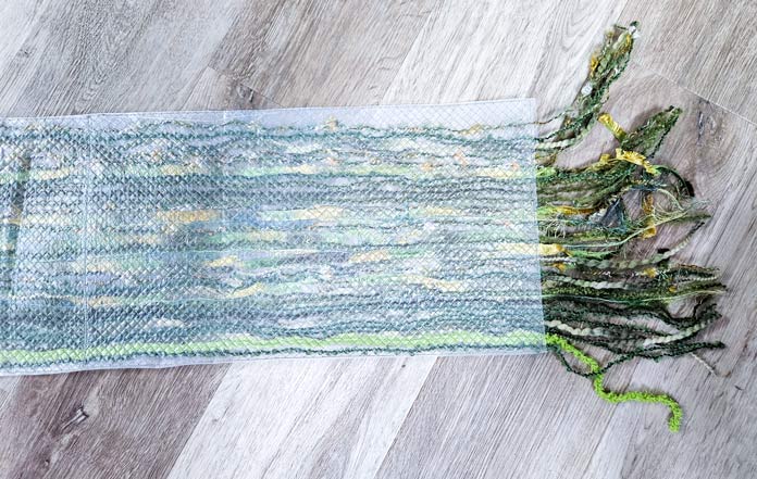 A piece of plastic with green yarn at one end