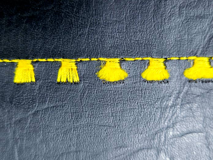 Tassel stitches in yellow thread on black vinyl