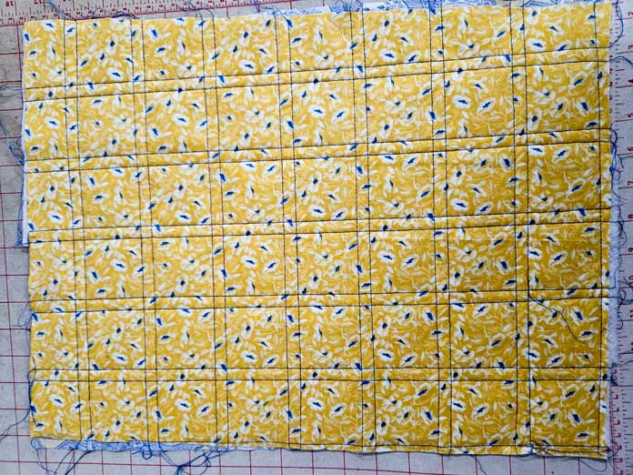 Blue lines of stitching on yellow fabric