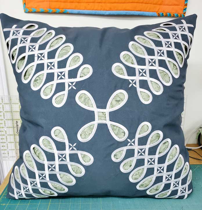 A green cushion cover with white cutwork designs; Husqvarna Viking Designer Sapphire 85