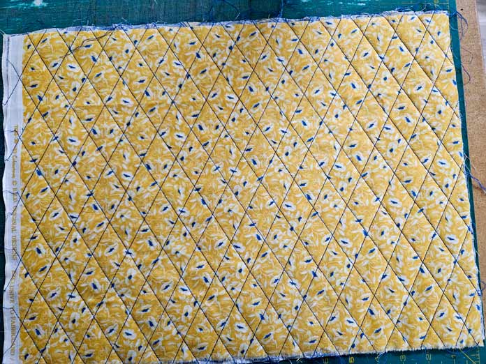 Yellow fabric with a diamond pattern stitched in blue thread