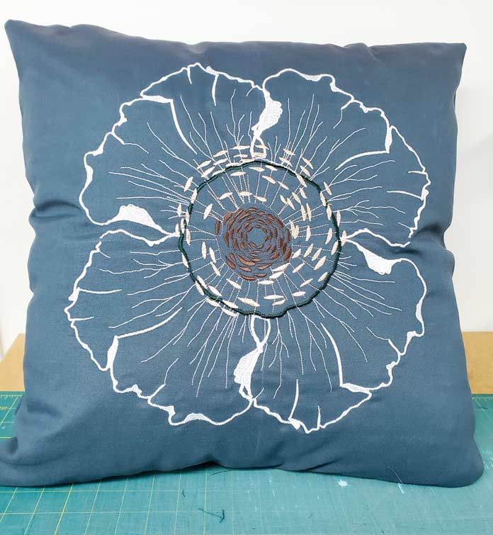 A cushion made with a white embroidered flower on green fabric. Husqvarna Viking Designer Sapphire 85, Inspira EZ Snip Curved Scissors