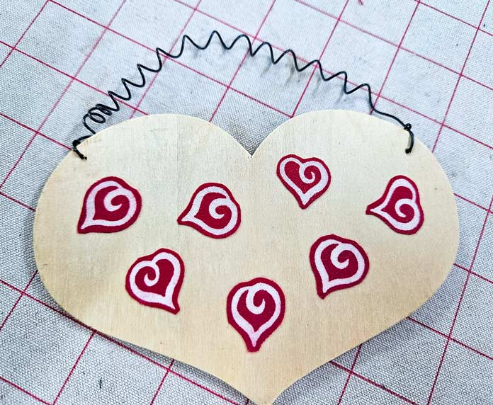 Fussy-cut red hearts on wood; Red hearts fussy cut with HeatnBond Ultra applied to the back; HeatnBond Ultra, fussy cutting, applique, fabric crafts.