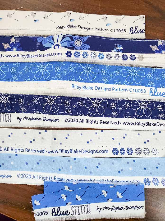 The selvages of the Blue Stitch collection by Riley Blake Designs. Blue Stitch collection by Riley Blake Designs, Husqvarna Viking EPIC2 sewing and embroidery machine, Husqvarna Viking Open Toe Foot, Singer Steam Press ESP2