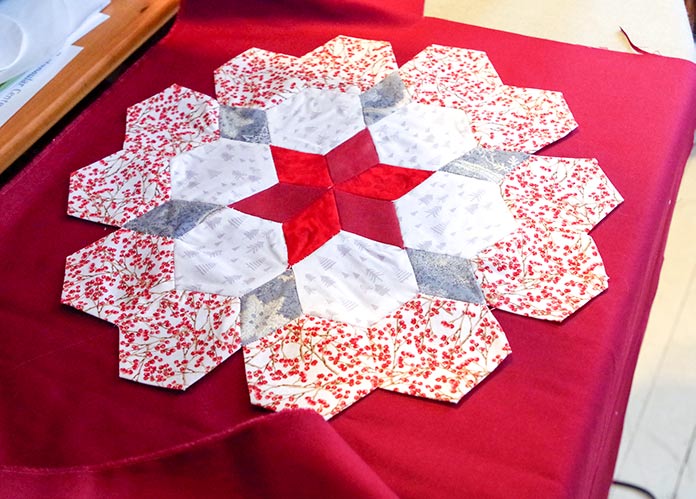The completed table topper is shown on the background ready for the final step of blind stitching them together. 