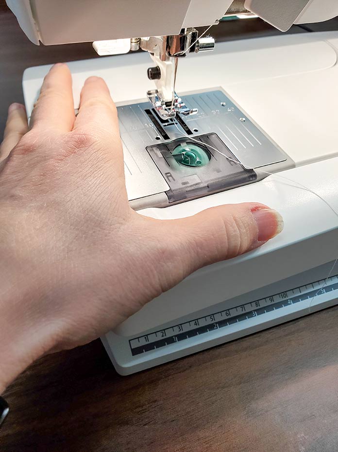 A hand resting on the accessory tray of the Husqvarna Viking Brilliance 75Q. Husqvarna Viking Brilliance 75Q sewing machine