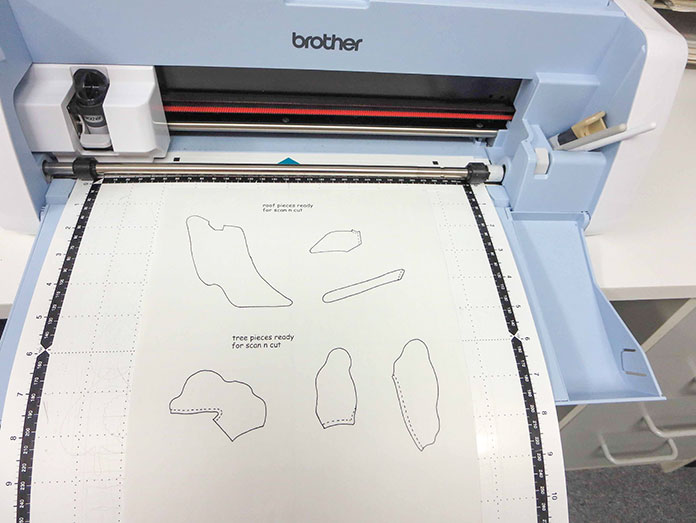 Paper pattern is placed on Brother scanning mat, Brother ScanNCut SDX225, Brother scanning mat, Brother fabric mat, Brother blue erasable marking pen, Heat n Bond Feather Lite, Brother color pen set