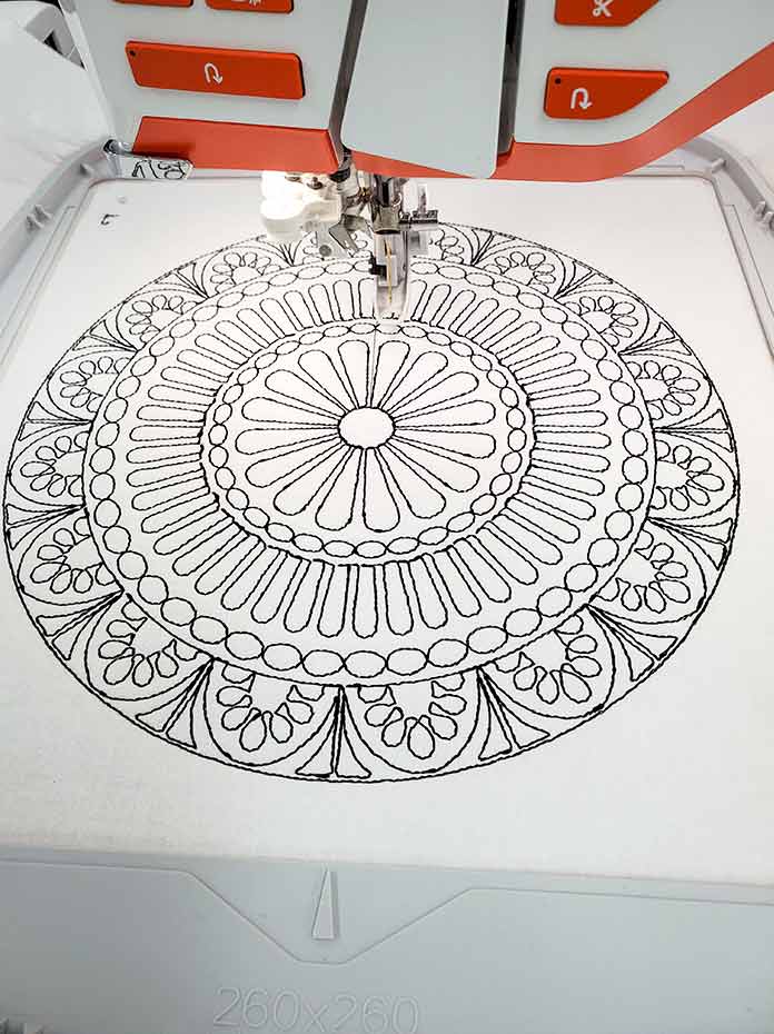 The first color of the embroidery design is almost complete with black thread on white fabric