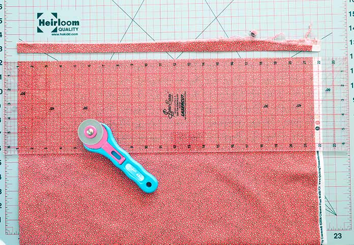 A ruler is aligned along the folded side of fabric in preparation for trimming