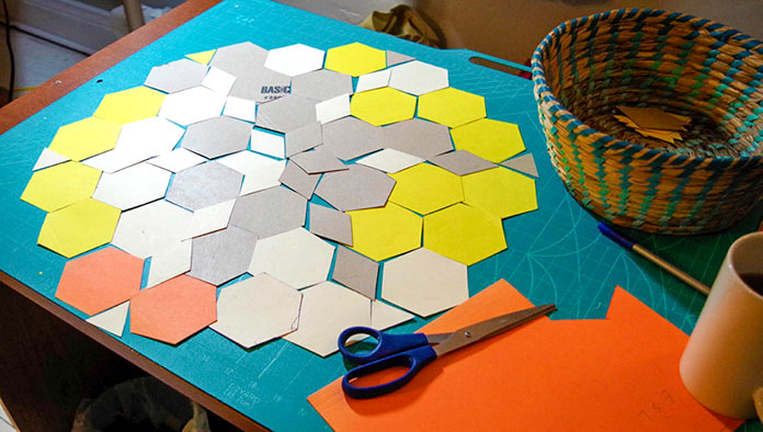 The scissors, cardboard, basket for storage and the cardboard hexies, diamonds and triangles are laid out to show one idea for the finished design. 