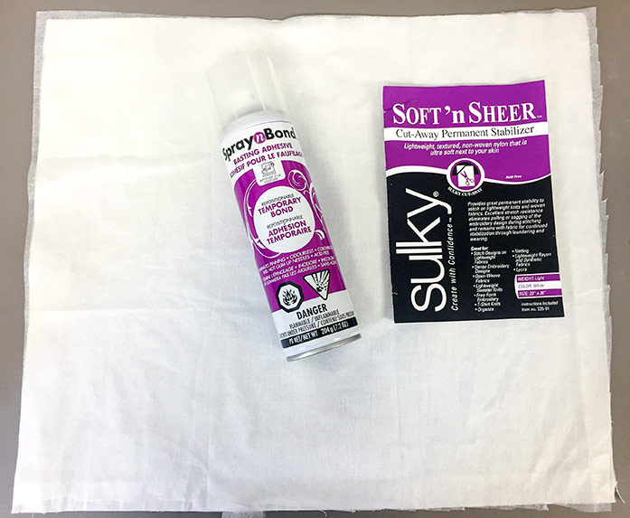 The Fabric Creations 100% cotton is layered with the Soft’n Sheer Cut-Away Permanent Stabilizer, and shown with the Spray n Bond Basting Adhesive and a package of Soft’n Sheer Cut-Away Permanent Stabilizer.