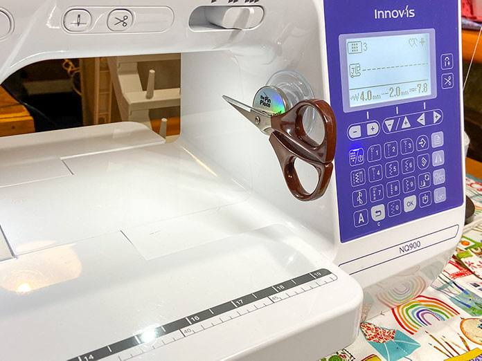 The Grabbit Scissor Spot/Pin Place Magnetic Holder attaches to the sewing machine with a suction cup and can be placed in multiple spots to hold either scissors or pins magnetically.