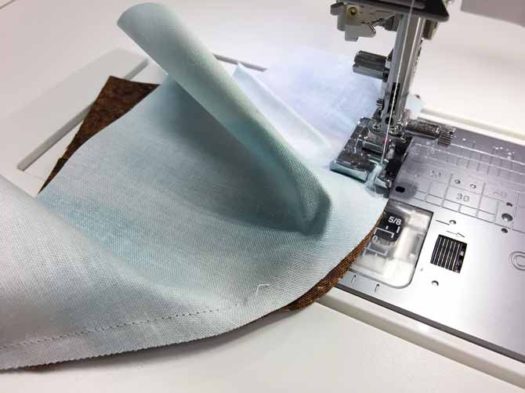 Block with right sides together under sewing machine being stitched.
