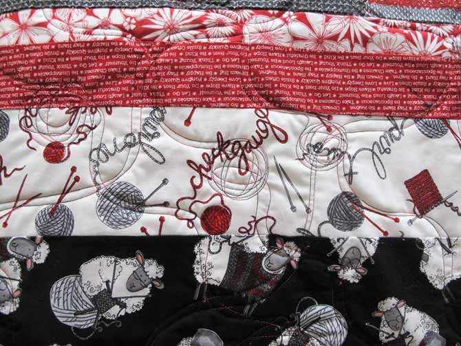 The quilting mimics the print on the fabric, balls of yarn and meandering yarn.