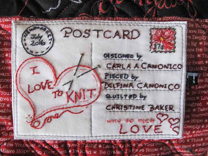 The finished quilt label on the red fabric of the I Love to Knit quilt