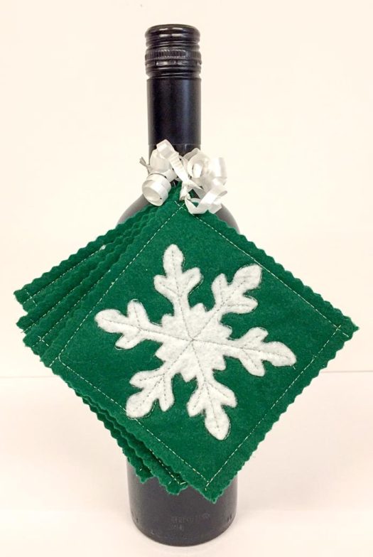 Snowflake coasters attached to a bottle of wine and ready for gift giving, Kunin Rainbow ClassicFelt (green and white), Sulky Holoshimmer and Hi-tak Glue