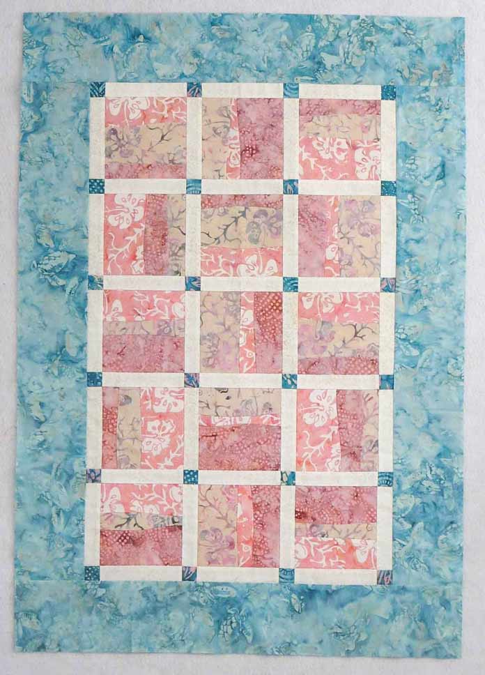 Quilt top with borders added; Curved strip-piecing using Banyan Batiks Island Vibes creates a sweet baby quilt. Free pattern!!