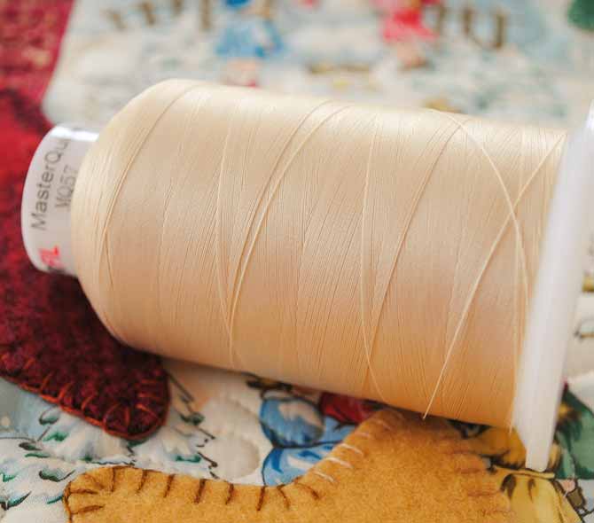 A cone of Master Quilter thread from WonderFil is displayed on a Christmas tablerunner.