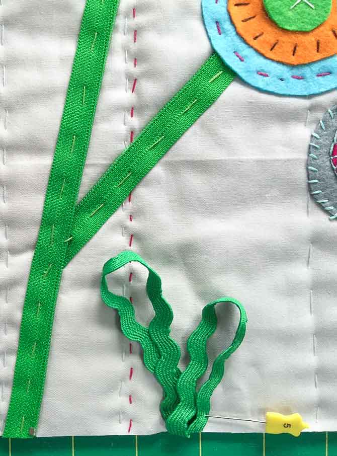 Loop rick rack at bottom of quilt to create grass. Pin and then tack down.