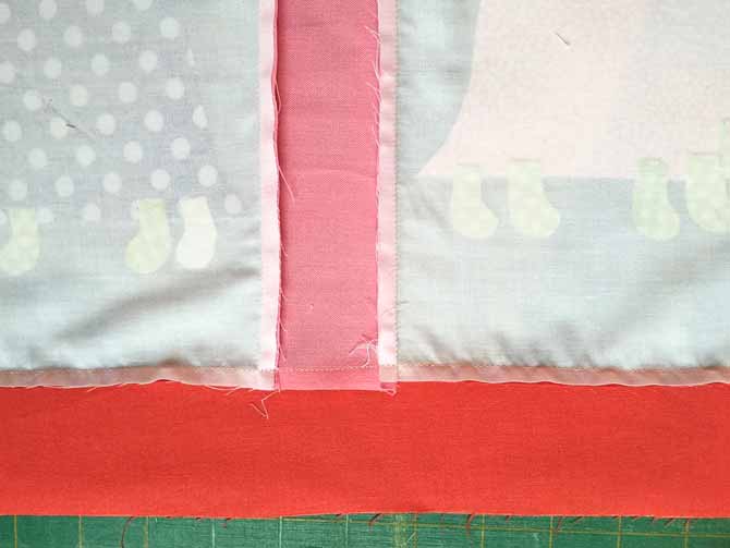 The wrong side of the quilt top is shown with the fabric being pressed to the dark fabric.