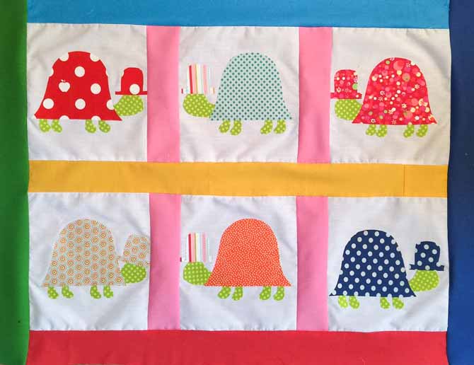 Quilt top with fused fabric turtles on a white background with various colors for sashing and border.