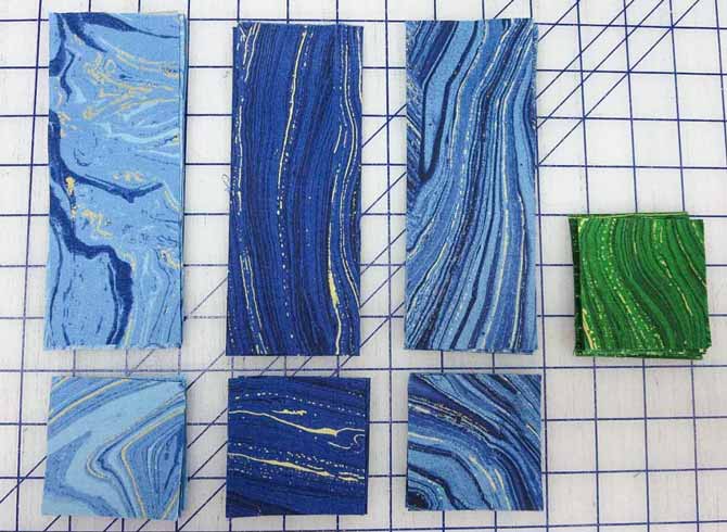 Blue Sandscapes strips and blue and green squares cut for the pieced blocks in the border