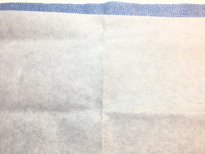 Tear Away stabilizer is pinned to the wrong side of the background fabric prior to stitching.