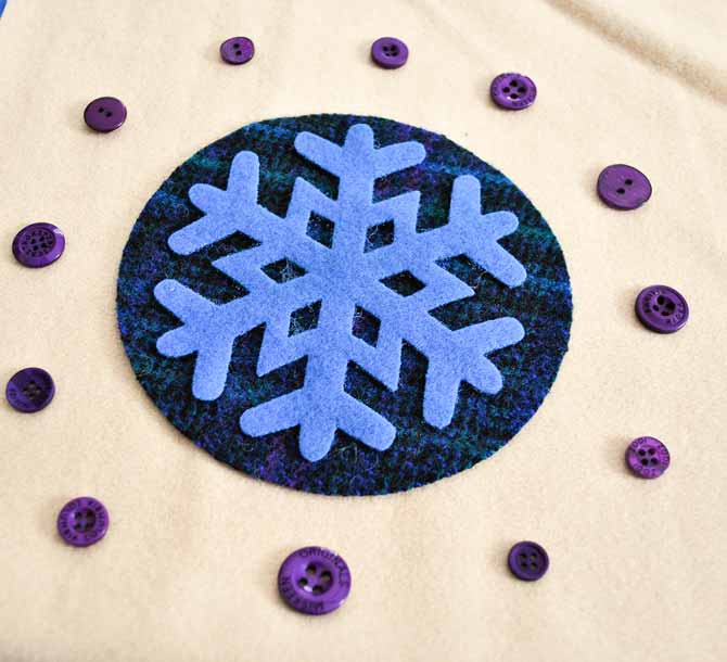 The wool applique shapes and buttons are arranged on the background
