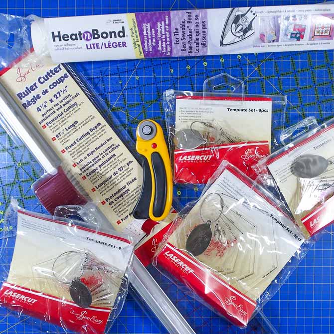 A variety of quilting tools and templates lying on a blue cutting mat